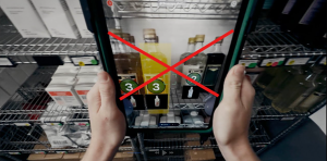 Starbucks employee using a tablet-based AI inventory tool to scan product shelves in a store